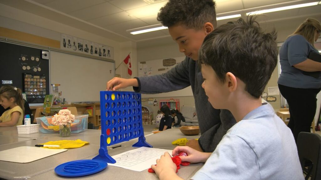 Two boys are playing a word-themed version of connect-4.